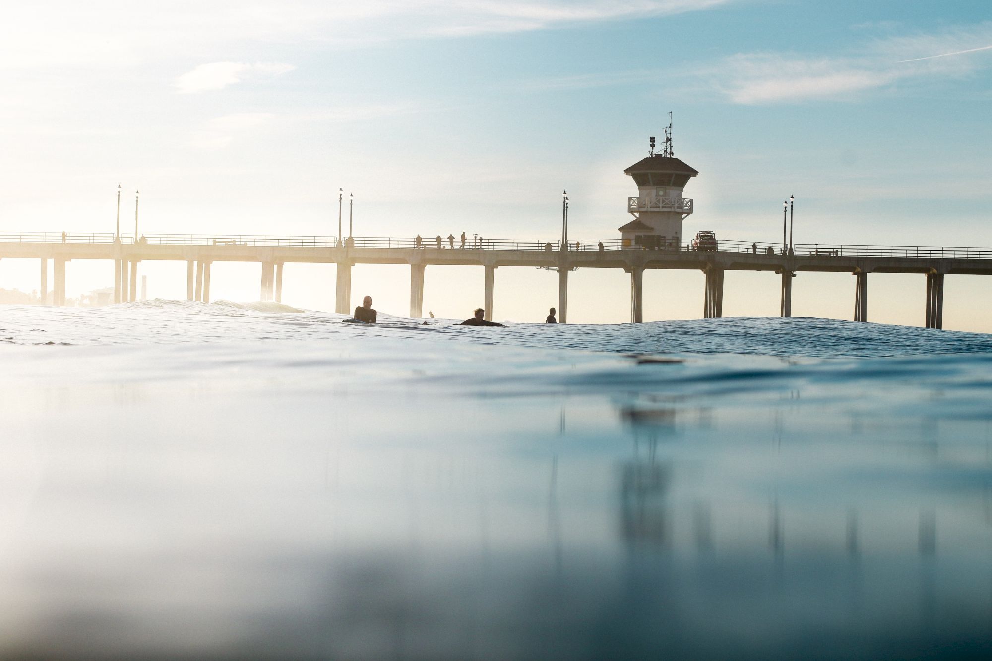 Pier with a tower, people walking, calm sea and clear sky.